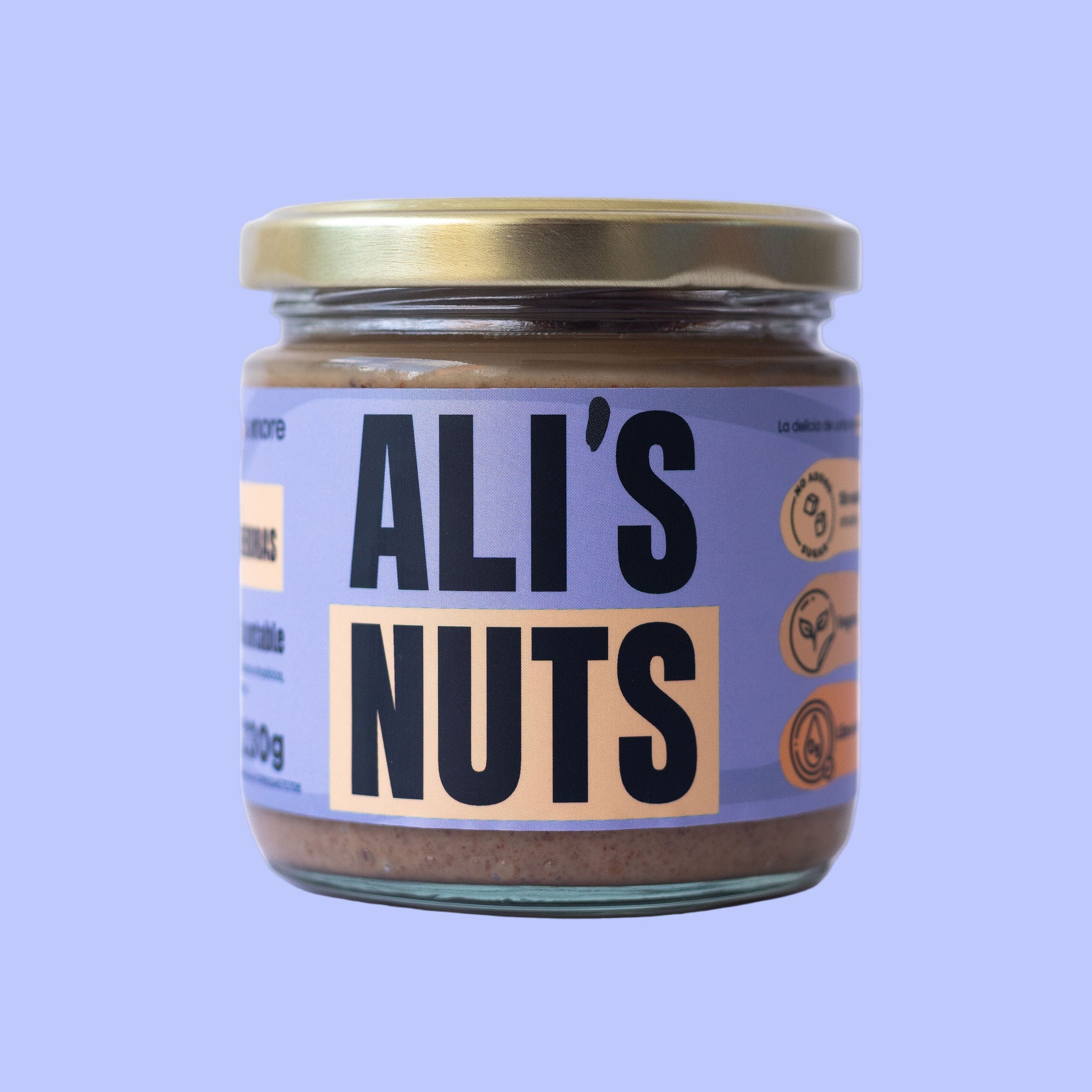 mantequilla de almendras Ali’s Nuts con tapa dorada y etiqueta lila sobre fondo púrpura